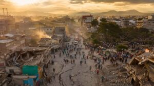 Vista aérea de una ciudad latinoamericana con calles agrietadas, edificios dañados y multitudes evacuando tras el doble terremoto que sacudió Venezuela en 2026